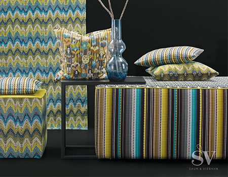 Arrangement von einem Sitzhocker, passenden Kissen und Gardine