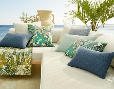 Ein beiges Sofa mit grünen und blauen Kissen.